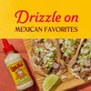A bottle of Cholula Cremosa Cilantro Lime sauce is featured next to tacos promoting its use on Mexican favorites.