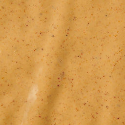 A close-up shot of a creamy orange-colored sauce with small red and black specks.
