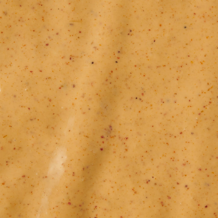 A close-up shot of a creamy orange-colored sauce with small red and black specks.