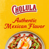 A bottle of Cholula Original Hot Sauce next to a plate of Mexican food with a fried egg, avocado, and radishes.