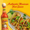 A bottle of Cholula Original Hot Sauce next to a plate of Mexican food.
