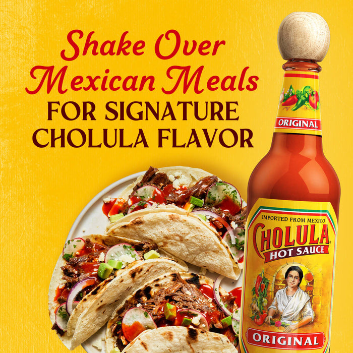 A bottle of Cholula Original Hot Sauce next to a plate of delicious Mexican tacos.