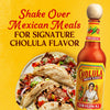 A bottle of Cholula Original Hot Sauce next to a plate of delicious Mexican tacos.