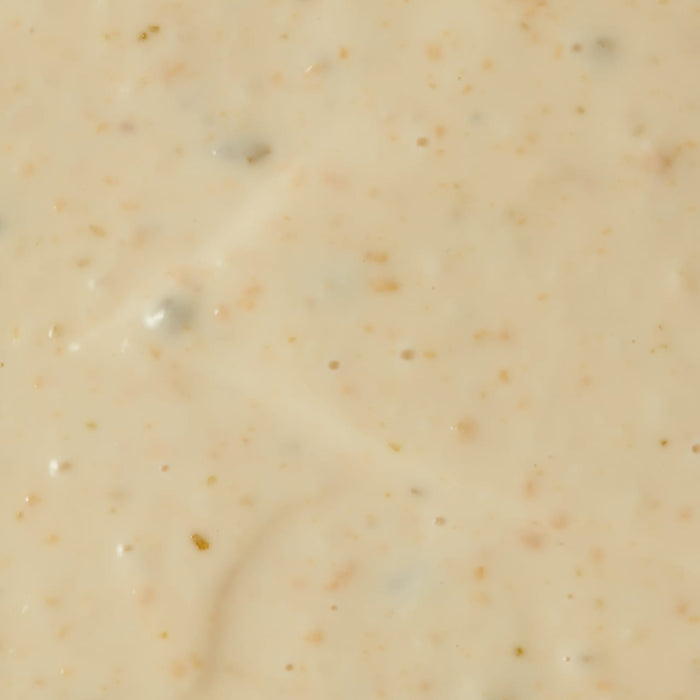 A close-up of a creamy white sauce with small brown flecks.
