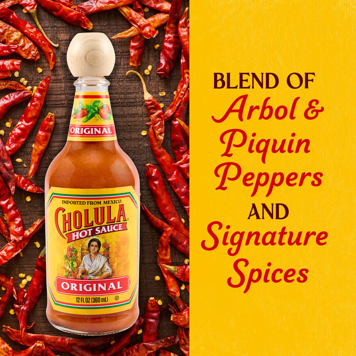 A bottle of Cholula Original Hot Sauce is surrounded by dried red chili peppers, with text describing it as a blend of Arbol &amp; Piquin Peppers and Signature Spices.