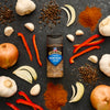 McCormick's Roasted Garlic &amp; Vegetable spice blend is showcased amidst fresh ingredients like garlic, onions, peppers, and spices, highlighting its versatility in cooking.