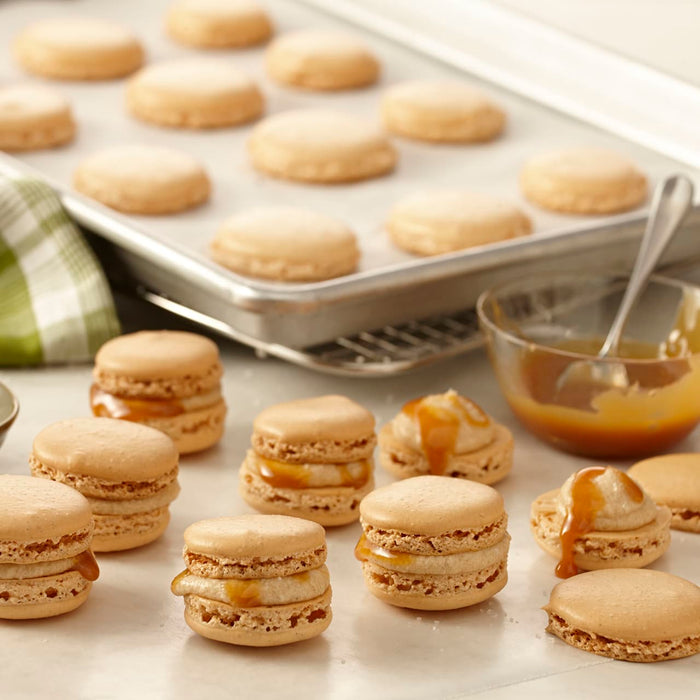 A close-up of caramel macarons on a white surface.