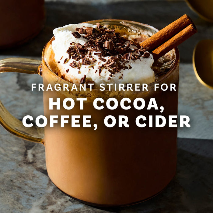 A mug of hot cocoa topped with whipped cream, chocolate shavings, and a cinnamon stick, suggesting a fragrant and flavorful beverage.