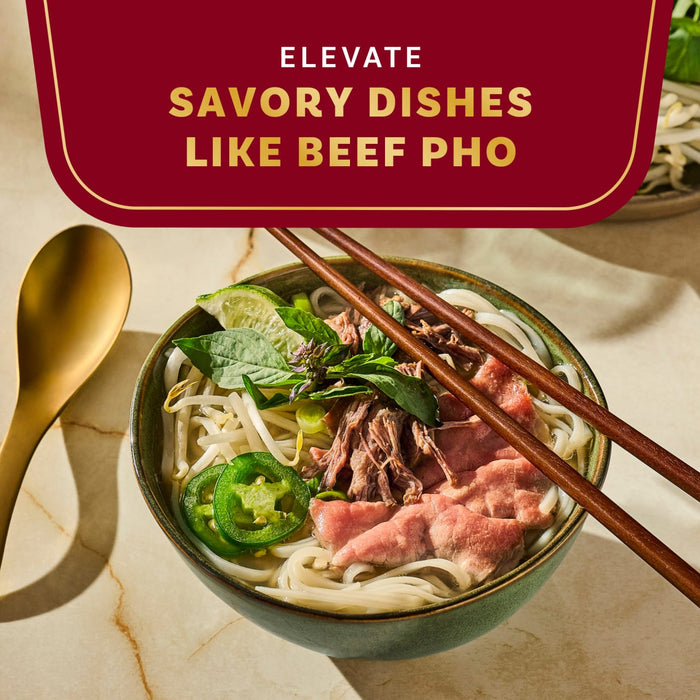 A bowl of beef pho is shown with chopsticks and a spoon, highlighting the dish's savory qualities.