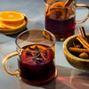 Two glasses of mulled wine garnished with orange slices and spices, evoking a warm and festive atmosphere.