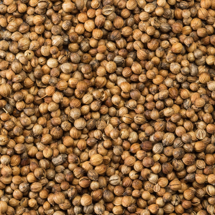 A close-up shows a pile of coriander seeds, showcasing their round shape and light brown color.