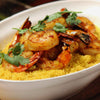 A bowl of couscous topped with grilled shrimp and cilantro.