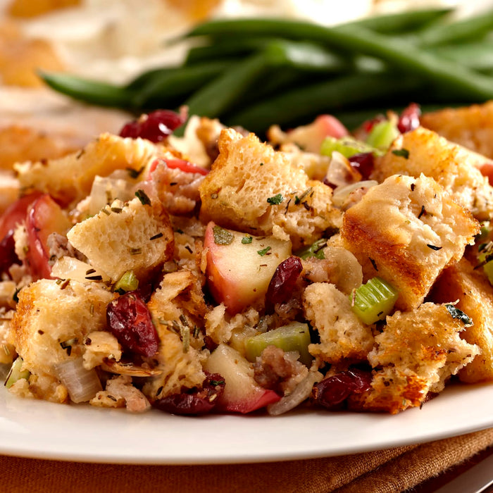 A close up of a plate of stuffing with cranberries, apples, and celery.