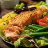 A plate of salmon with green beans, potatoes, and tomatoes.