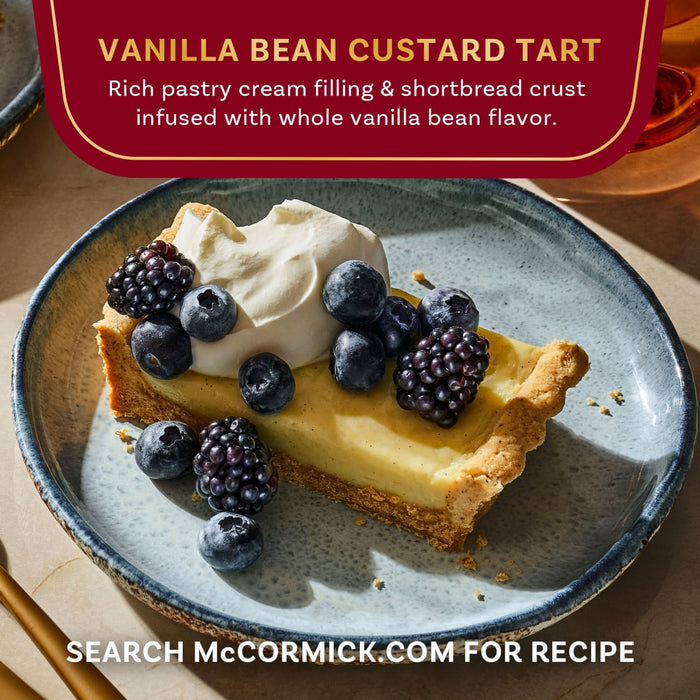 A slice of McCormick Vanilla Bean Custard Tart topped with whipped cream and berries is displayed on a blue plate.
