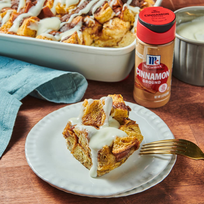 A plate of cinnamon bread pudding with a fork and a container of McCormick Cinnamon Ground.