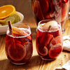 Two glasses of refreshing sangria with fruit slices and a cinnamon stick, perfect for a summer gathering.