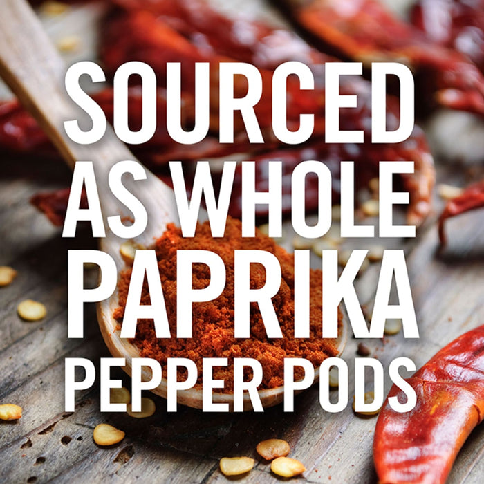 A wooden spoon filled with paprika powder, surrounded by whole red pepper pods.