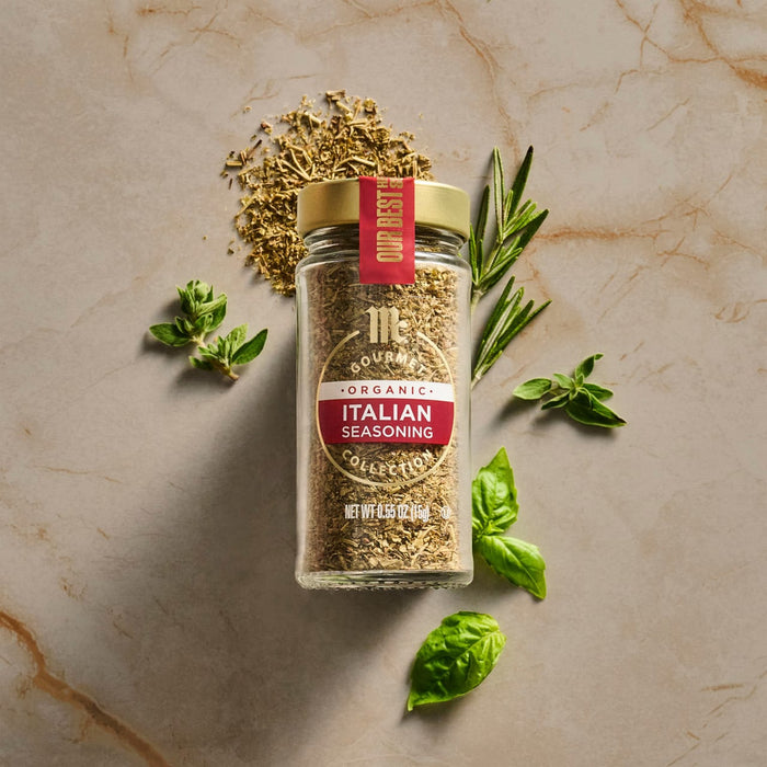 A jar of McCormick Italian Herb Seasoning is surrounded by fresh basil and rosemary sprigs, highlighting the product's natural ingredients.