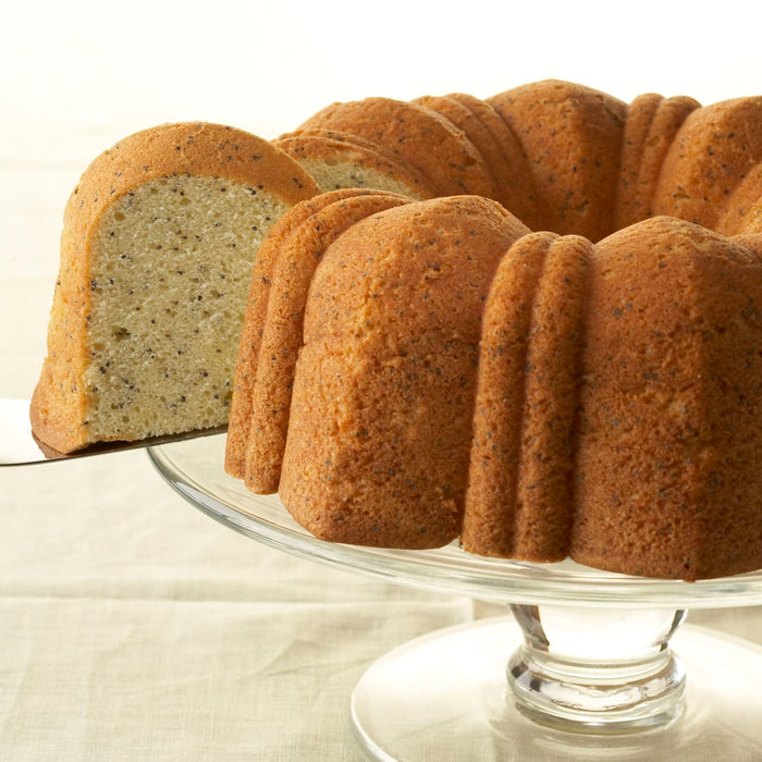 A poppy seed cake on a glass cake stand.