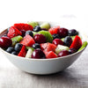A white bowl filled with a fruit salad of watermelon, kiwi, strawberries, blueberries, and cherries.