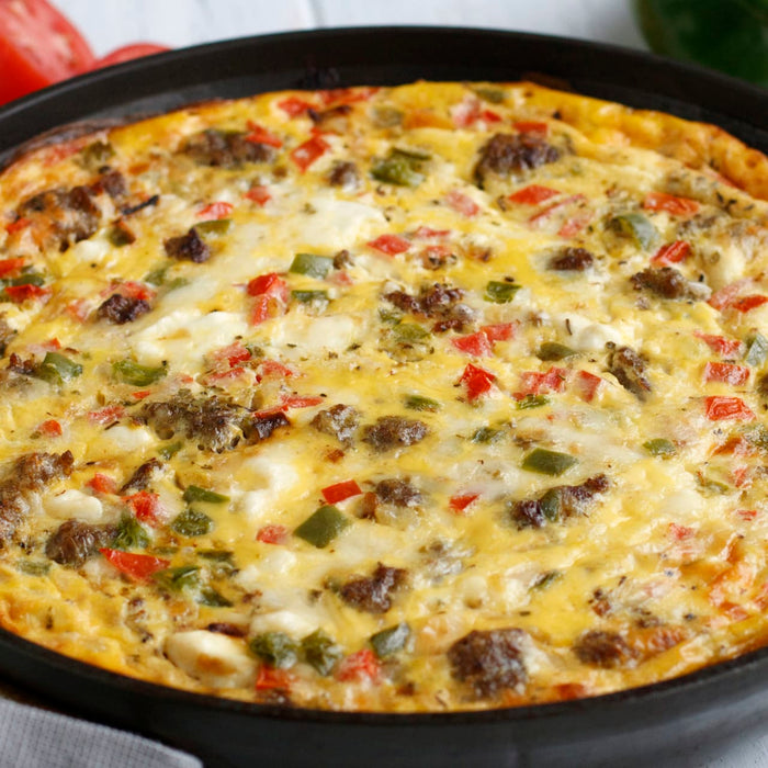 A close-up of a breakfast casserole with sausage peppers and cheese.