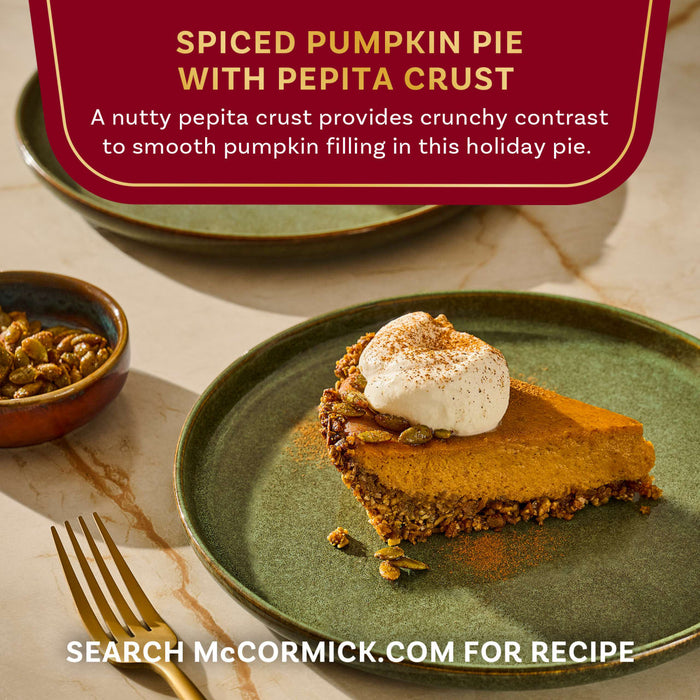 A slice of McCormick Spiced Pumpkin Pie with Pepita Crust topped with whipped cream is displayed on a green plate.