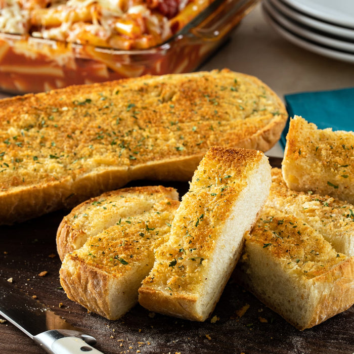 A close-up of a wooden cutting board with several slices of toasted garlic bread.