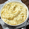 A bowl of mashed potatoes with parsley on top.