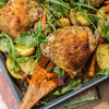 A close-up of a delicious meal of roasted chicken, potatoes, carrots, and arugula.
