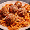 Spaghetti with meatballs and tomato sauce topped with parmesan cheese.