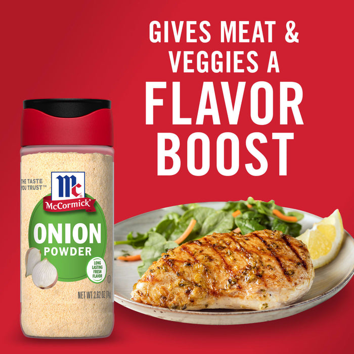 A bottle of McCormick Onion Powder next to a plate of grilled chicken with a side of greens and a lemon wedge.