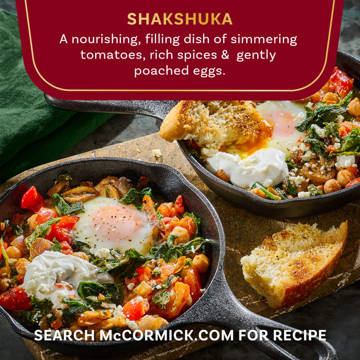 A close-up of two cast iron skillets filled with McCormick Shakshuka, a nourishing dish of simmering tomatoes, rich spices, and gently poached eggs.