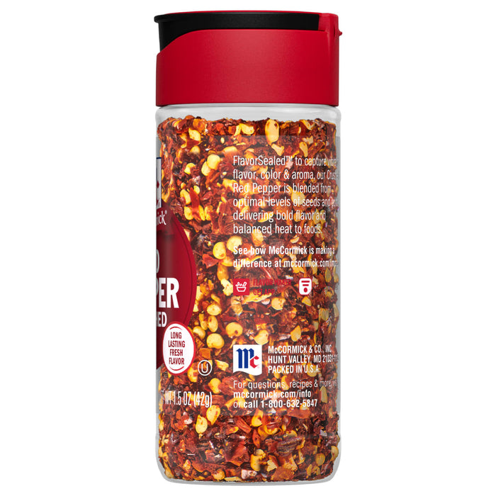 A McCormick Red Pepper spice jar with a red lid and a clear glass body filled with red pepper flakes.