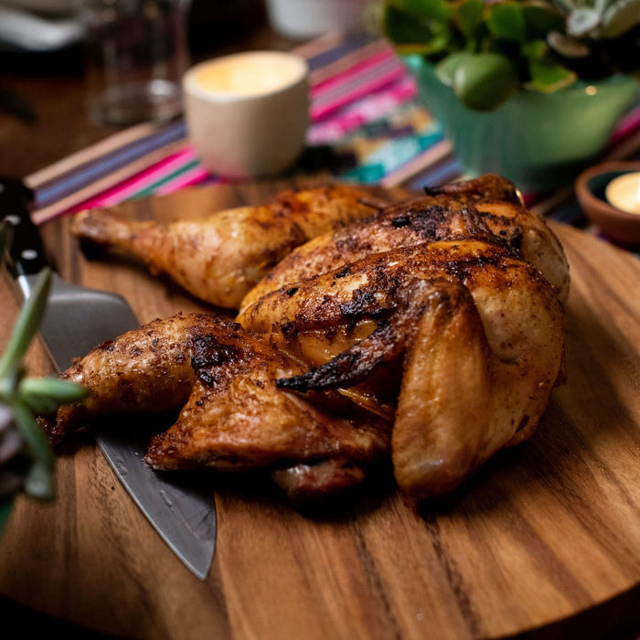 A close-up of a roasted chicken on a wooden cutting board.
