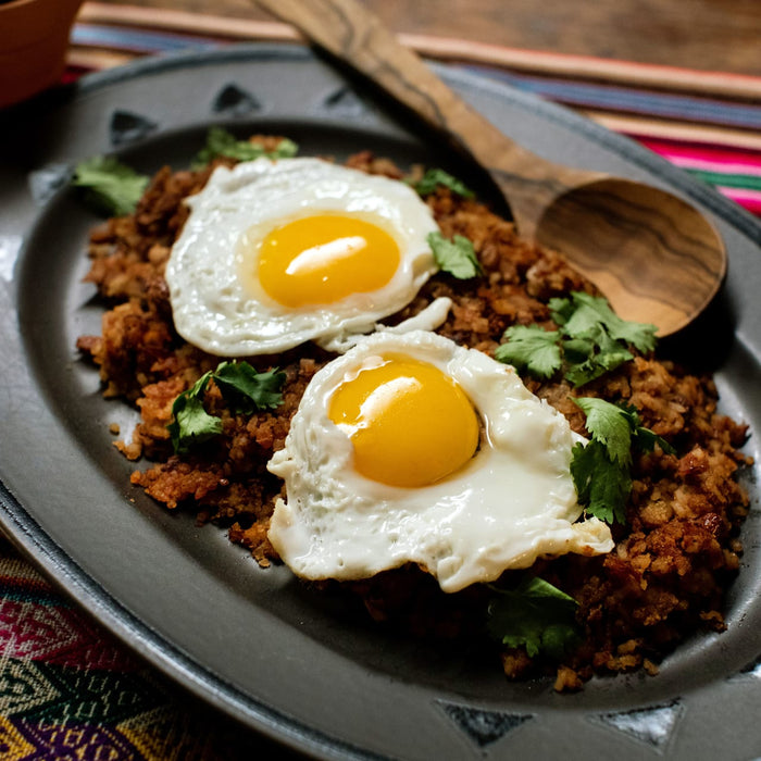 A plate of fried rice with two fried eggs and cilantro.
