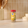 A bottle of Mccormick Everything Bagel Seasoning Assorted Form 4.8 Oz stands on a marble countertop in a bright kitchen setting.