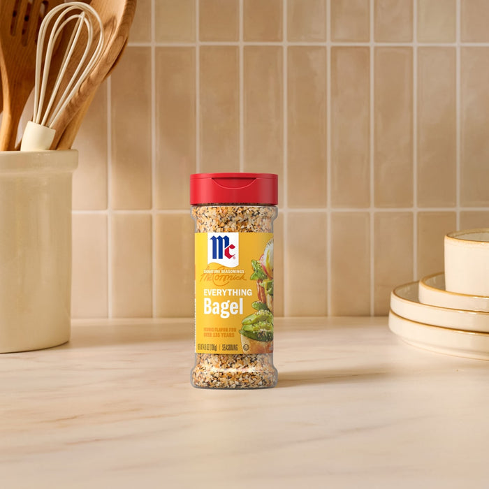 A bottle of Mccormick Everything Bagel Seasoning Assorted Form 4.8 Oz stands on a marble countertop in a bright kitchen setting.