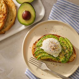 A slice of toasted sourdough topped with sliced avocado and a poached egg is generously sprinkled with Mccormick Everything Bagel Seasoning Assorted Form 4.8 Oz.