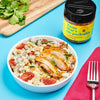 A bowl of corn salad with grilled chicken topped with Flavor Maker's im-peckable chicken topping seasoning.