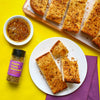 This image features garlic bread seasoned with Flavor Me Pasta-tively Obsessed pasta topping seasoning along with a dipping sauce on a vibrant yellow background.