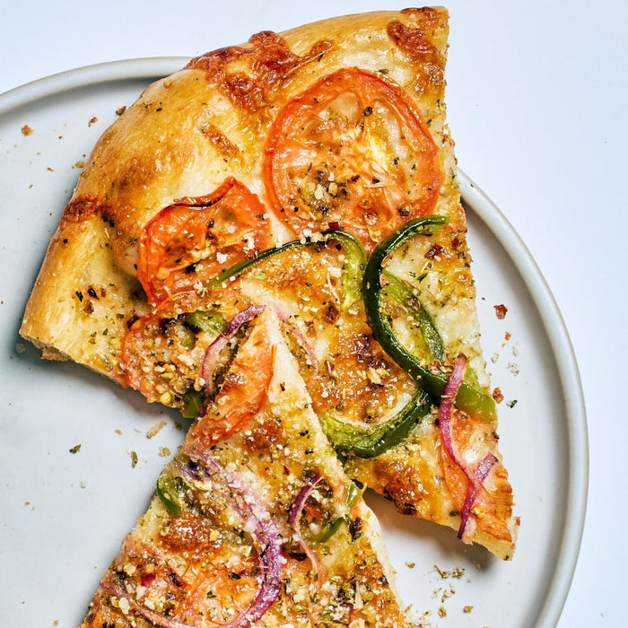 Two slices of pizza with tomato, green pepper, red onion, and cheese on a white plate.