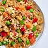 A bowl of fried rice with vegetables and sesame seeds.