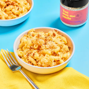 A bowl of mac and cheese topped with Flavor God's You Mac Me Smile mac and cheese topping seasoning.