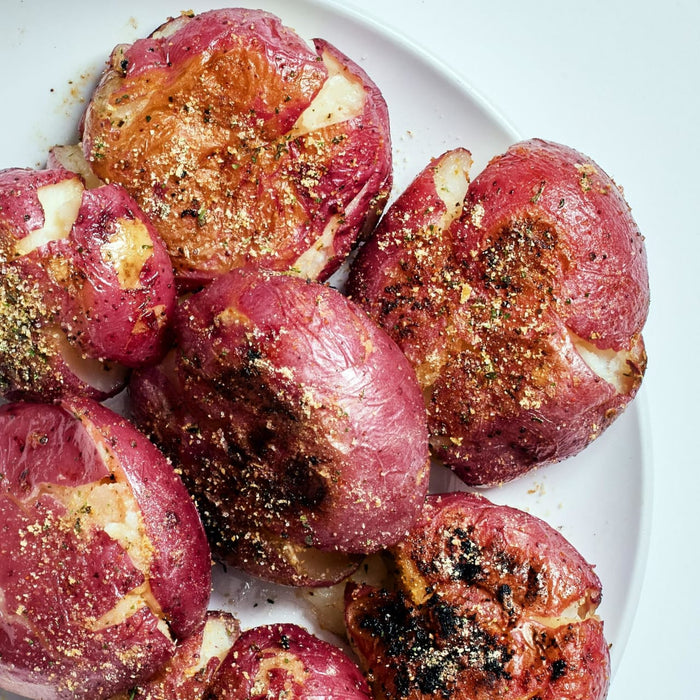 A plate of roasted red potatoes with herbs and spices.