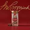 A glass jar of Mccormick Gourmet, 0.42 Oz Star Anise from the Gourmet Collection is displayed against a rich red background featuring the gold McCormick logo, with a few star anise pods resting beside the jar.