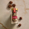 A glass jar of Mccormick Gourmet, 0.42 Oz Star Anise is displayed on a marbled surface, with several whole star anise pods artfully arranged around the bottle.
