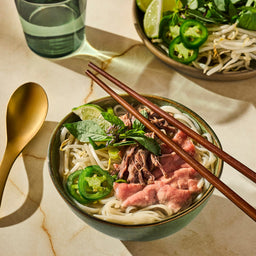 A beautifully prepared bowl of Vietnamese pho with beef, noodles, and fresh garnishes, representing a flavorful dish that can be made with seasonings from a Mccormick Gourmet, 0.42 Oz product.