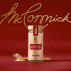 A glass jar of Mccormick Gourmet Garlic Truffle Salt, 2.25 Oz, is centered in a product shot against a rich red background, with a small golden spoon holding a sample of the salt next to the jar.