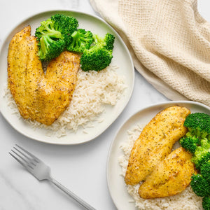 Two plates featuring golden fish fillets, white rice, and steamed broccoli, all seasoned with Mccormick Culinary Lemon &amp; Pepper Seasoning Salt.